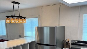 Una cocina compacta con un refrigerador de acero inoxidable, un horno empotrado y una lámpara colgante.