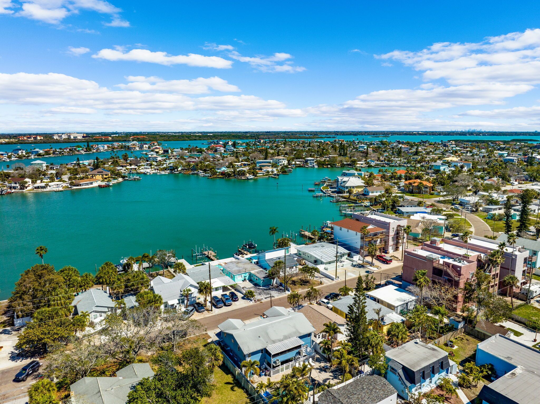 Vue aérienne d’une zone résidentielle côtière, avec des maisons, une marina et une vaste étendue d’eau.