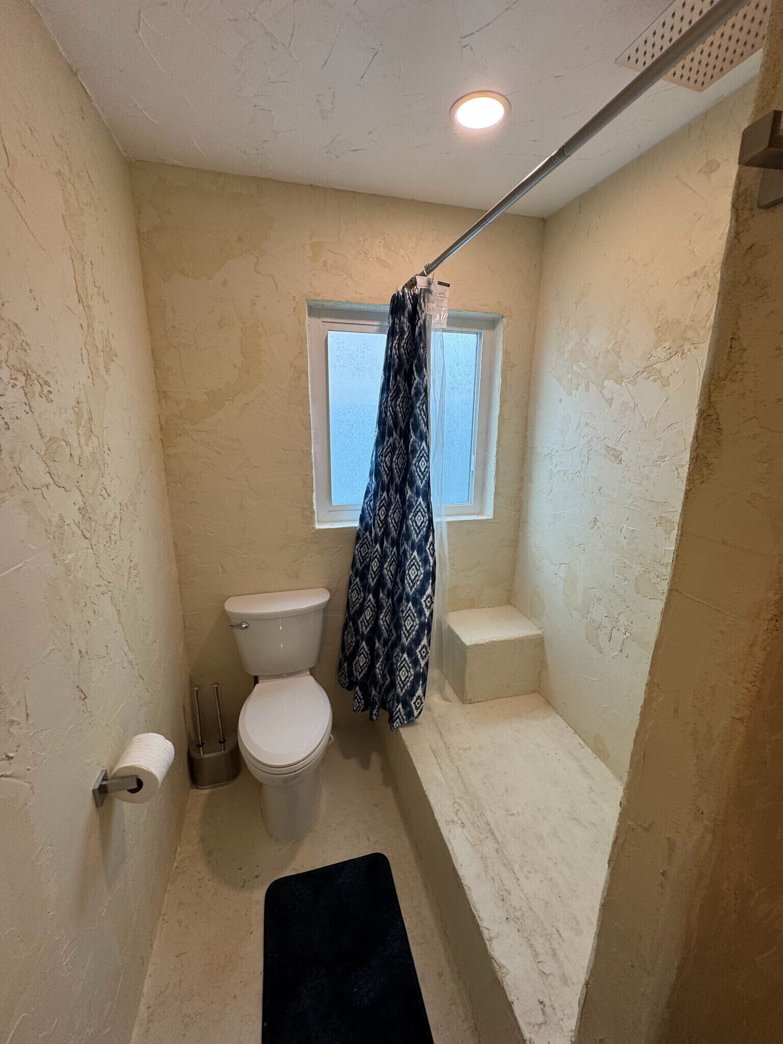 Ein kleines Badezimmer mit Toilette, Fenster und Duschvorhang.