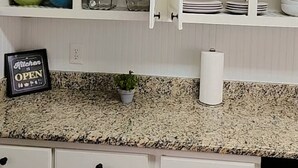 A kitchen with white cabinets, a granite countertop, and various dishes and kitchenware.