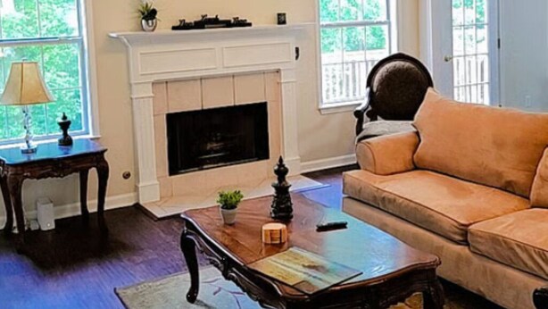 A living room with a fireplace, a sofa, a coffee table, and a ceiling fan.