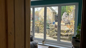 A room with a large sliding glass door leading to a stone wall and garden.
