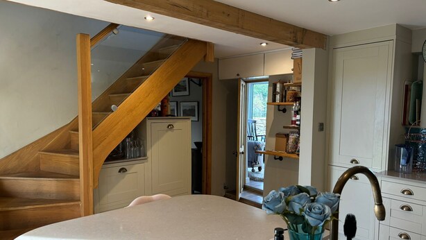 A kitchen with a wooden staircase, a large island, and a view into the dining area.