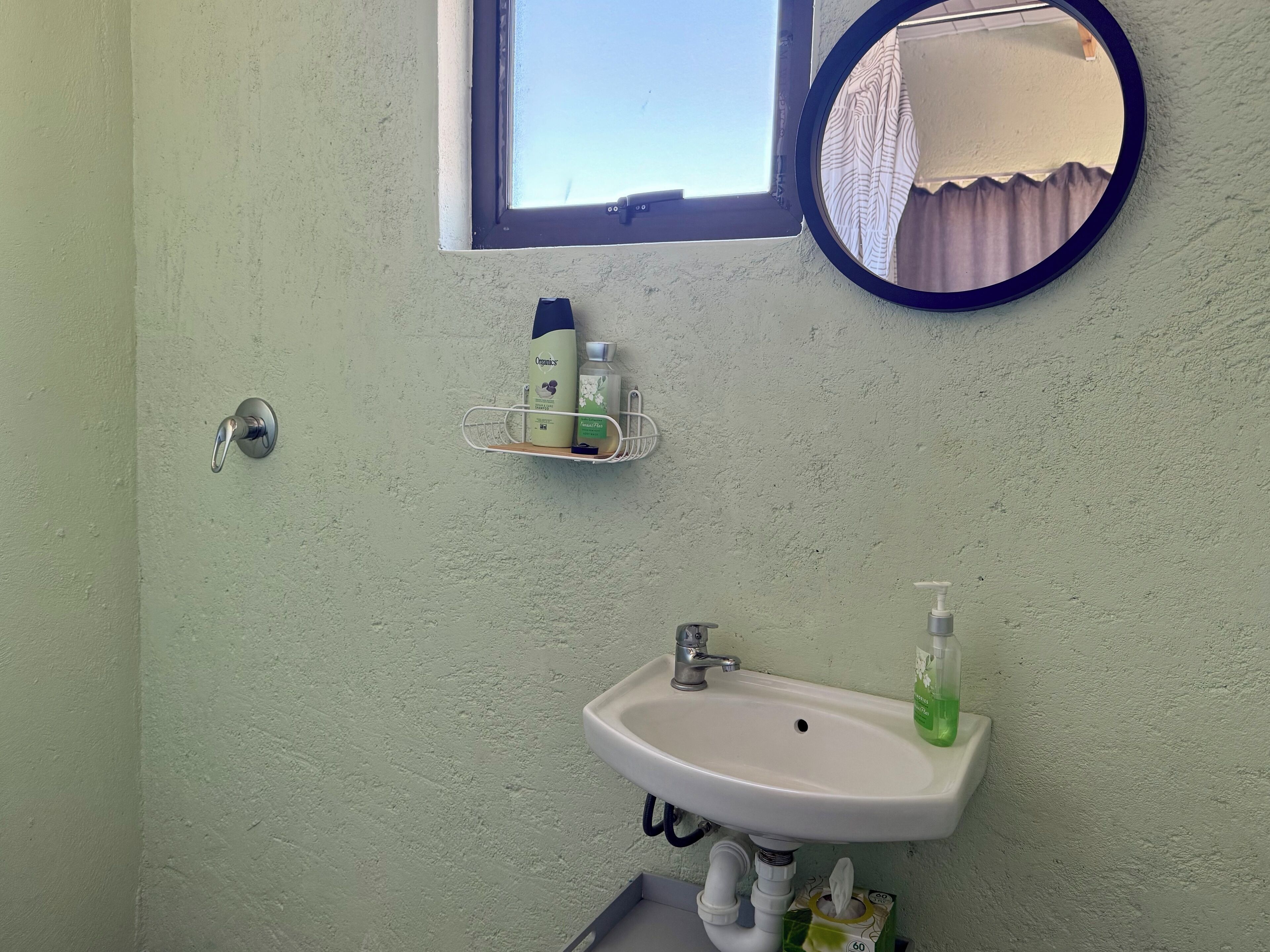 A bathroom with a white sink, a mirror, and a window.