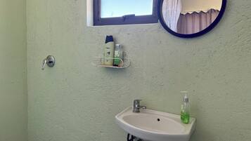 A bathroom with a white sink, a mirror, and a window.