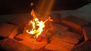 Un hogar con leña ardiendo, rodeado de ladrillos.