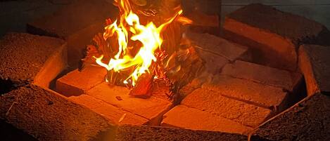 A fire pit with burning logs surrounded by bricks.