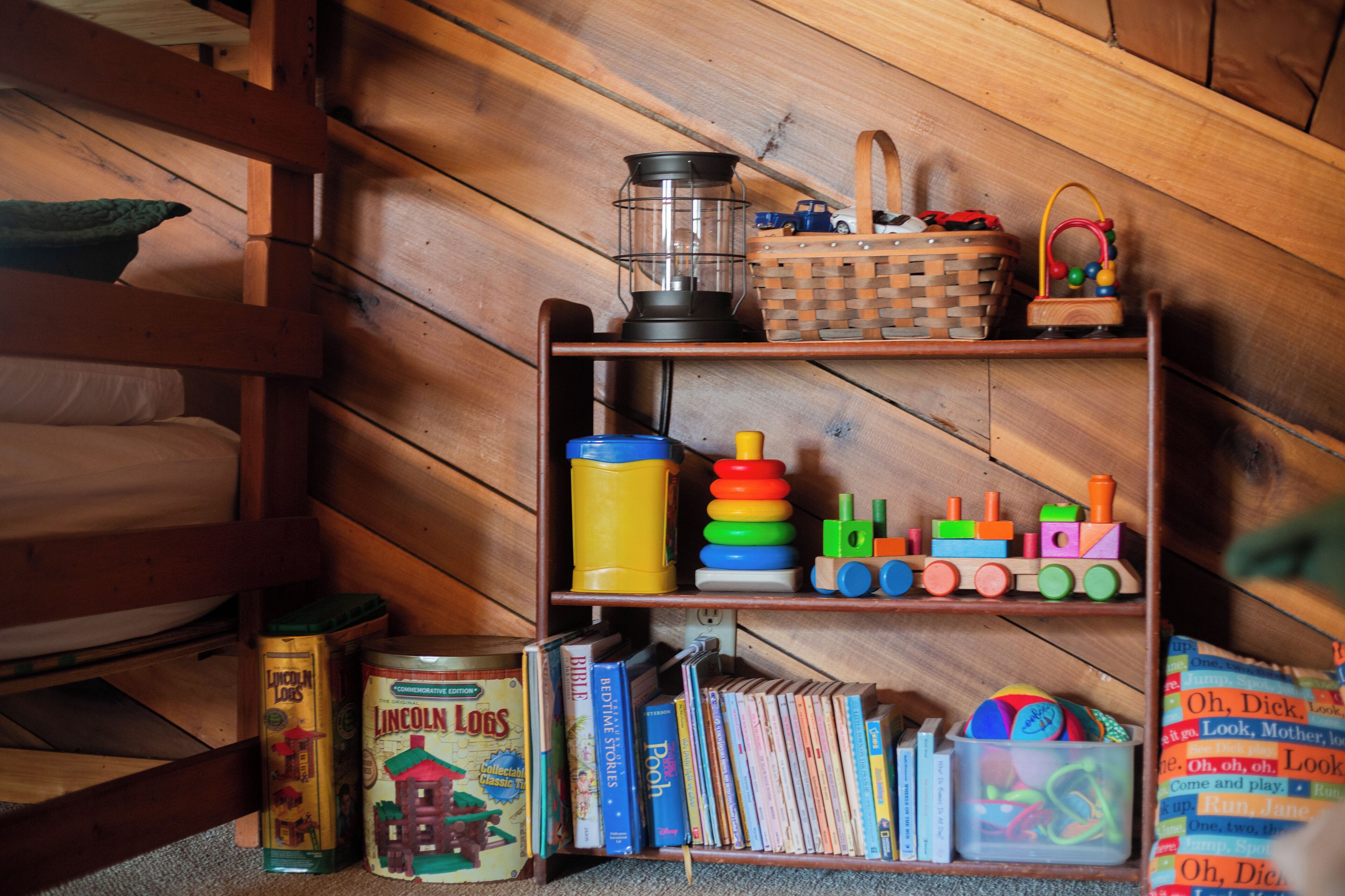 Estante de madeira com brinquedos infantis, livros e uma cesta.