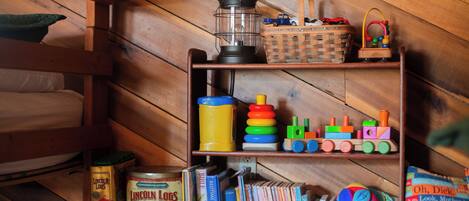 Estante de madeira com brinquedos infantis, livros e uma cesta.