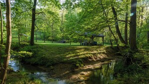 A serene park with a small stream, a picnic area, and a gazebo.