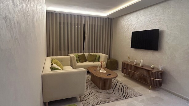 A modern living room with a sofa, a coffee table, and a TV mounted on the wall. - Charming studio Urban cozy studio (Casablanca)
