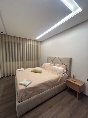 Un dormitorio moderno con cama, mesita de noche y lámpara de techo.