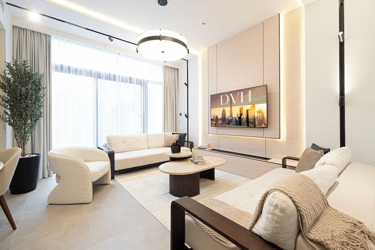Un salon moderne avec un canapé, des fauteuils, une table basse et un grand téléviseur.