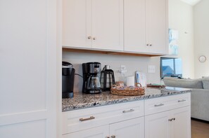Une cuisine avec des meubles blancs, une machine à café, un grille-pain et un panier en osier posé sur le plan de travail.