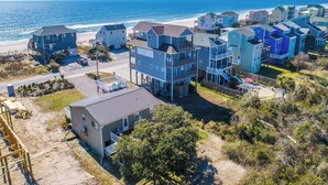 Una zona residencial costera con casas de varios pisos, una playa al fondo y un cielo despejado.