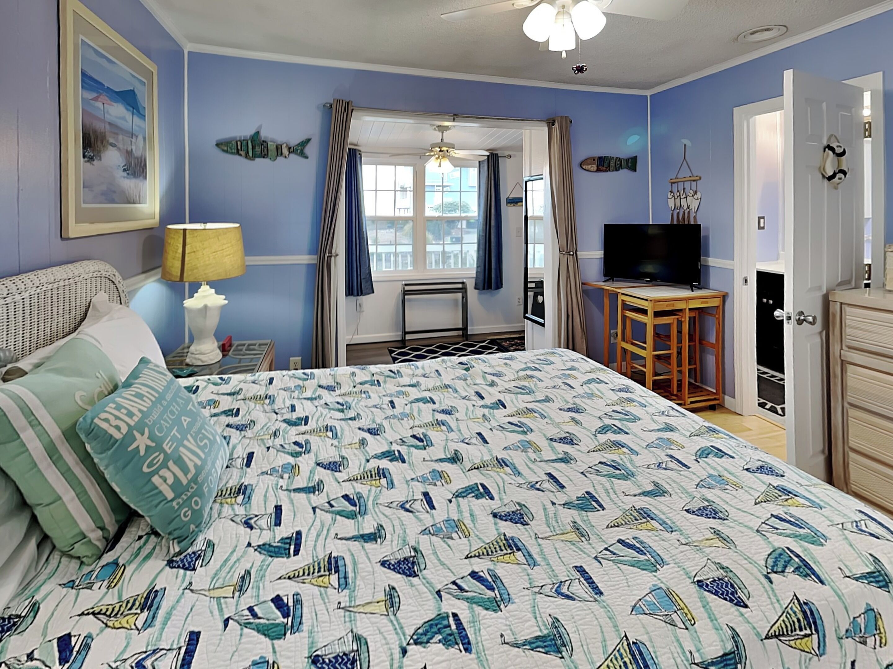 Een slaapkamer met een bed, een televisie, een bureau en een dressoir.