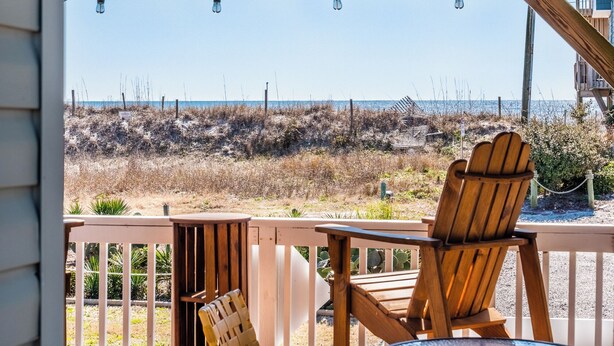 A wooden deck with two Adirondack chairs facing a beach. - In Good Sands by Topsail Realty (Sneads Ferry)