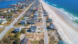 An aerial view of a coastal residential area with houses, a beach, and a road. - In Good Sands by Topsail Realty (Sneads Ferry)