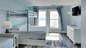 Un dormitorio con literas, un escritorio, un aparador, un televisor y una ventana con cortinas.