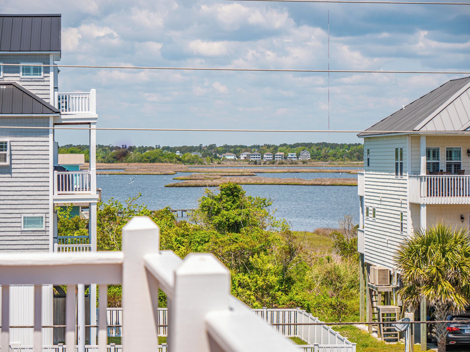 A coastal residential area with houses overlooking a body of water, featuring balconies and a clear view of the shoreline.