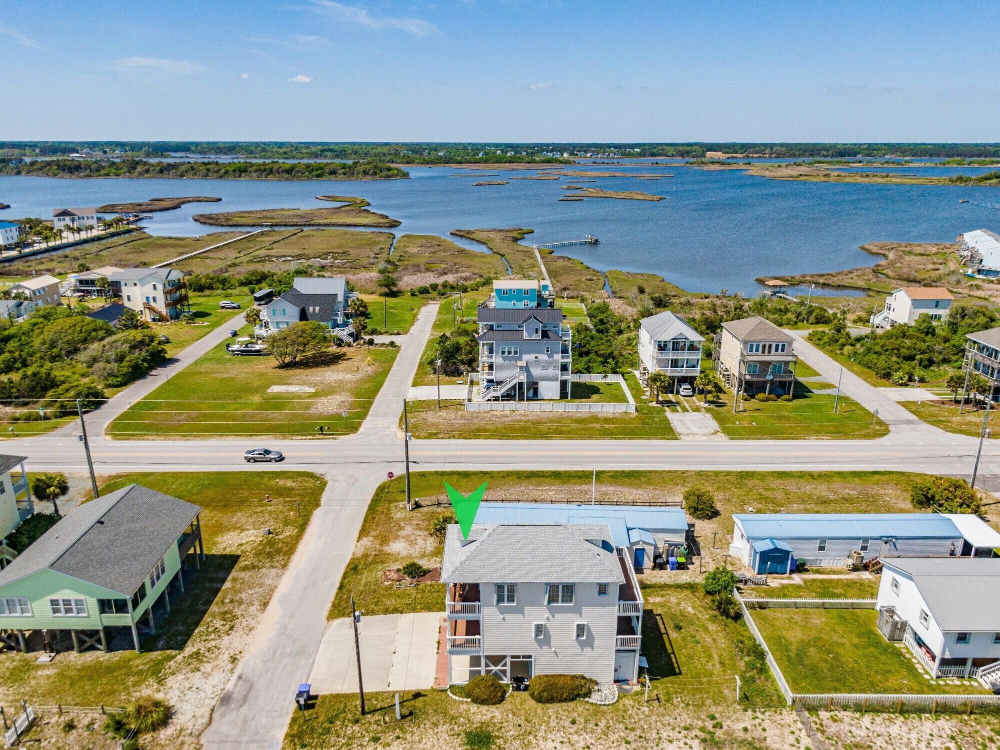 A coastal residential area with houses, a road, and a body of water.