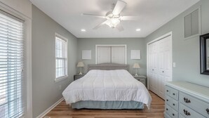 A bedroom with a bed, two bedside tables with lamps, a ceiling fan, and a dresser. - Skipper's Hideout by Topsail Realty (Sneads Ferry)