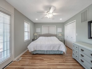 A bedroom with a bed, two bedside tables with lamps, a ceiling fan, and a dresser. - Skipper's Hideout by Topsail Realty (Sneads Ferry)