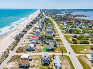 An aerial view of a coastal residential area with houses, roads, and a beach.