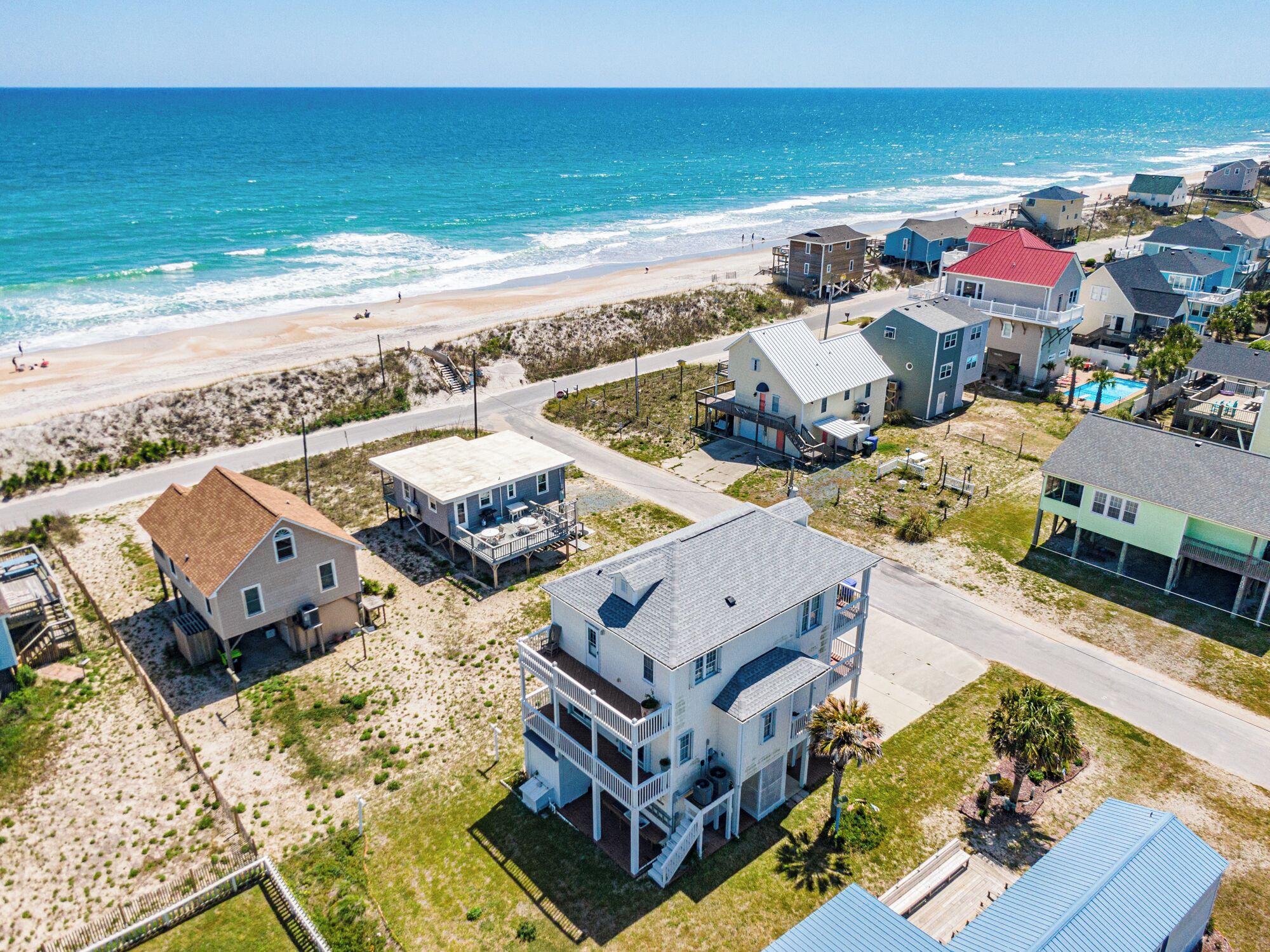 A coastal residential area with houses, a beach, and a road.