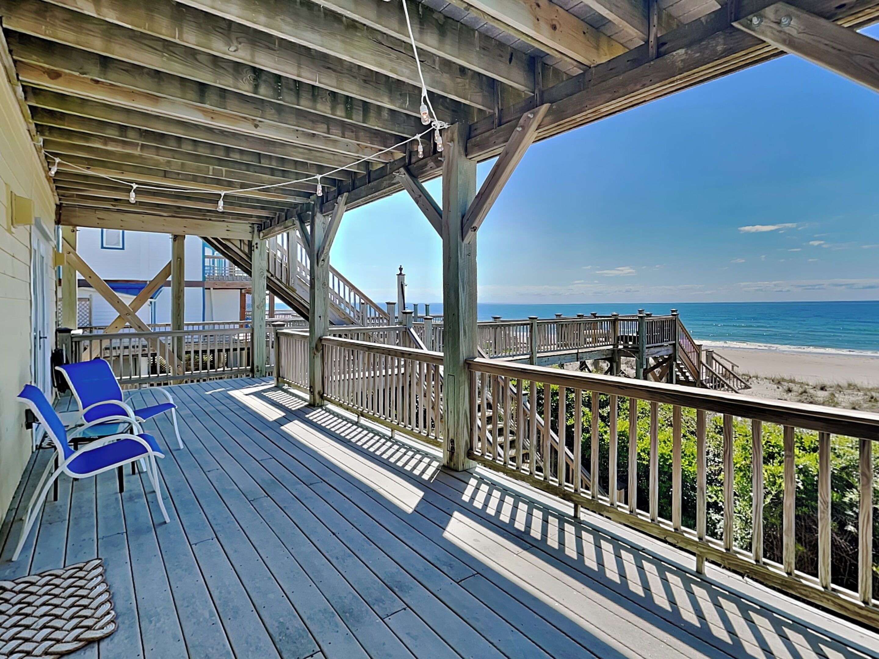 A wooden deck with a view of the beach and ocean.