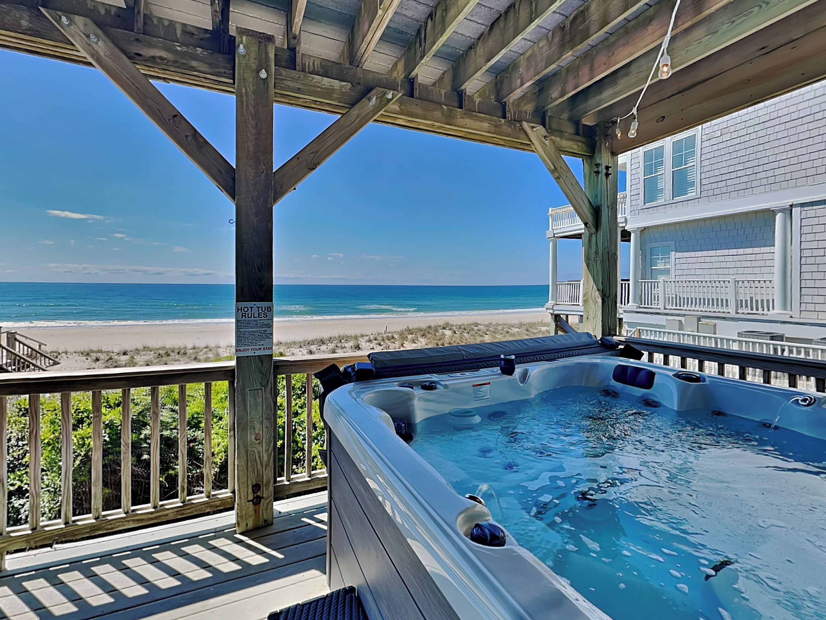 Un jacuzzi en una terraza de madera con vista a la playa y el océano.