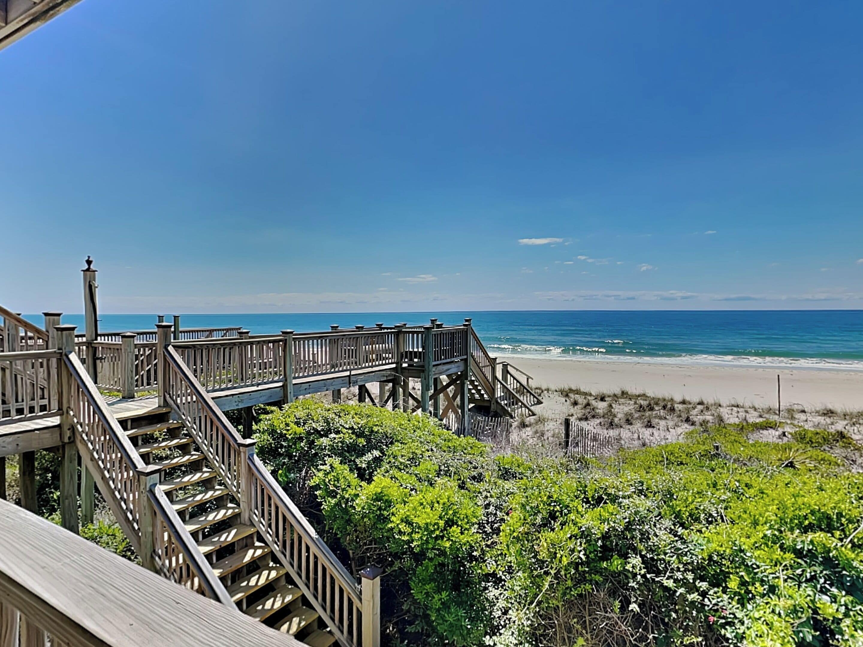 A wooden boardwalk leading to a beach with clear skies.