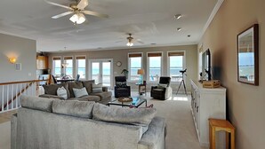 A spacious living room with a grey sofa, a coffee table, and a balcony with a view of the ocean. - Sunny Side Up by Topsail Realty (Sneads Ferry)