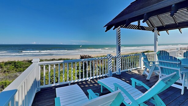 A wooden deck with white railings and turquoise Adirondack chairs overlooking a beach. - Blue Me A Wave by Topsail Realty (Sneads Ferry)