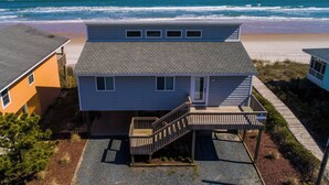 A beachfront house with a covered porch and a staircase leading to the entrance. - Hicks by Topsail Realty (Holly Ridge)