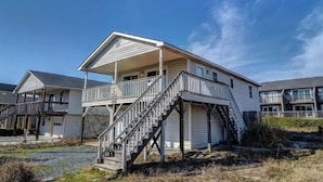 A two-story building with a covered porch and a staircase leading to the upper level. - Sassy Seahorse by Topsail Realty (Holly Ridge)
