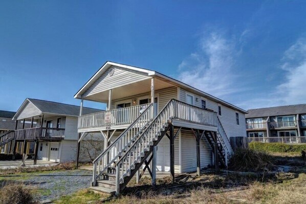 A two-story building with a covered porch and a staircase leading to the upper level. - Sassy Seahorse by Topsail Realty (Holly Ridge)