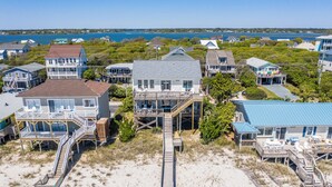 A coastal property with multiple buildings, including a large house with a deck and a smaller house with a blue roof. - You're The Tops by Topsail Realty (Holly Ridge)
