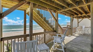 A wooden deck with white chairs overlooking a beach. - You're The Tops by Topsail Realty (Holly Ridge)