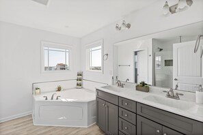 Un baño moderno con una bañera grande, un tocador con espejo y una ventana que proporciona luz natural.