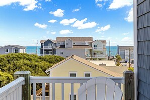 Una zona residencial costera con varias casas, una terraza de madera y vista al océano.