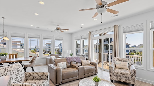 A spacious living room with a large sectional sofa, a round coffee table, and a ceiling fan.