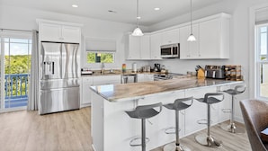 A modern kitchen with white cabinets, stainless steel appliances, and a central island with bar stools.