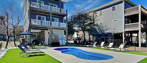 A two-story house with a swimming pool, a fenced yard, and a covered patio area.