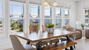 A spacious dining area with a wooden table, multiple chairs, and a potted plant.