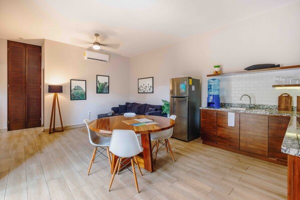 A modern kitchen with a central island, a dining area with a round table and chairs, and a built-in oven.