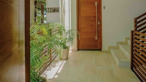 Un pasillo con una puerta de madera, una escalera y un candelabro.