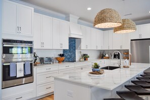 A modern kitchen with white cabinets, stainless steel appliances, and a large island with a sink.