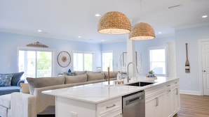Una cocina moderna con armarios blancos, una isla central con pileta e iluminación colgante.