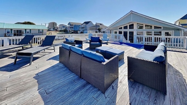 A wooden deck with wicker furniture and a white railing. - Bellcove by Topsail Realty (Holly Ridge)